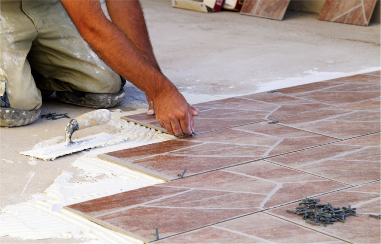 MIJ Technical Services worker installing ceramic floor tiles with spacers for accurate alignment