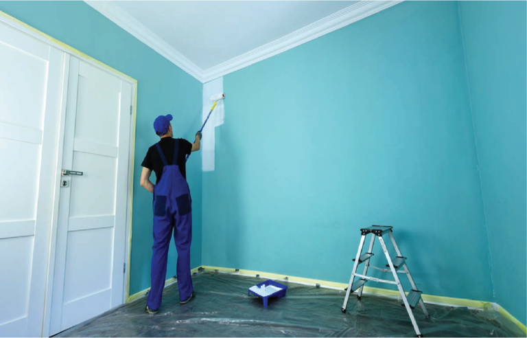 MIJ Technical Services painter using roller to repaint interior wall with protective floor cover