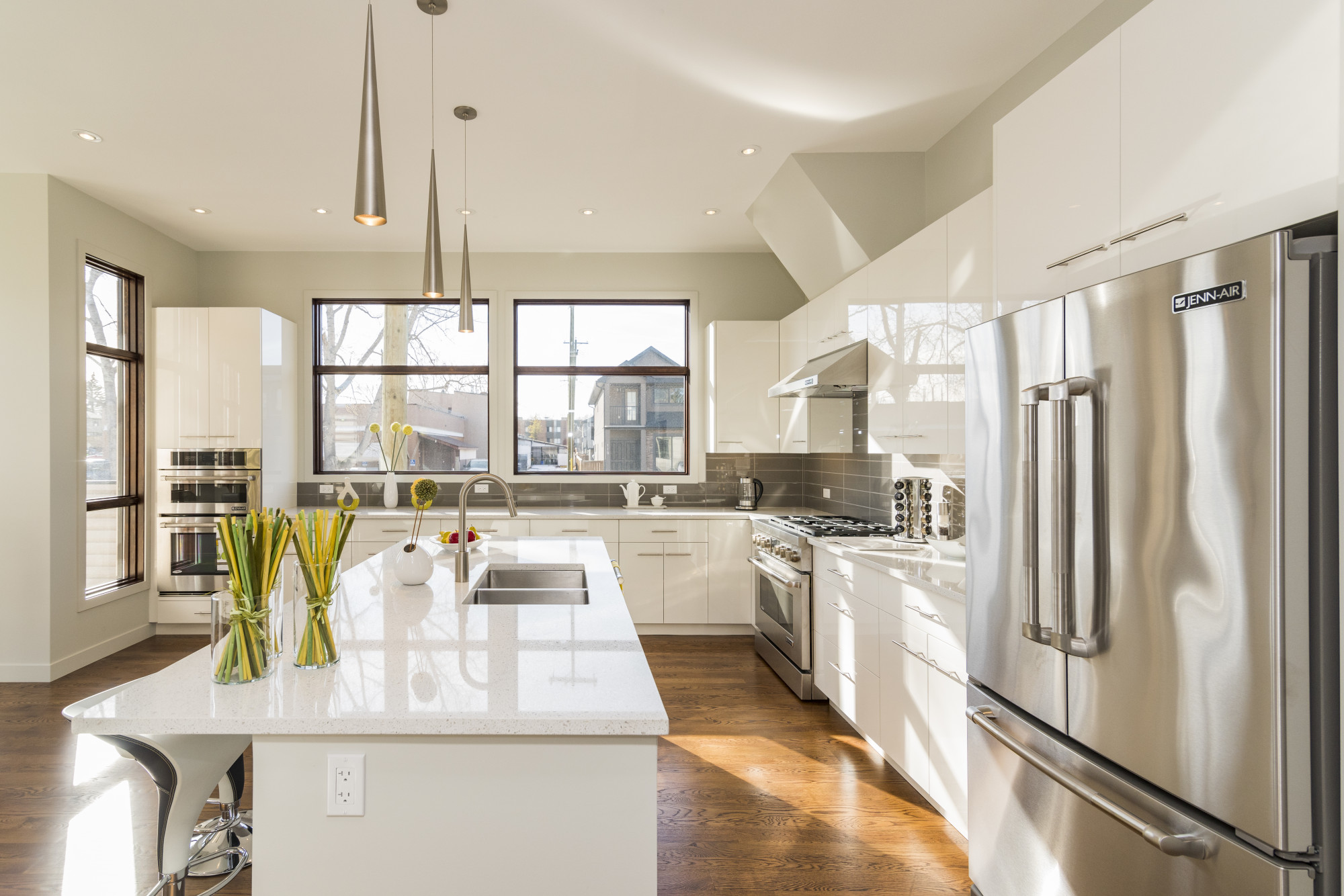 Modern kitchen interior with sleek white cabinets, stainless steel appliances, and large windows for natural light.